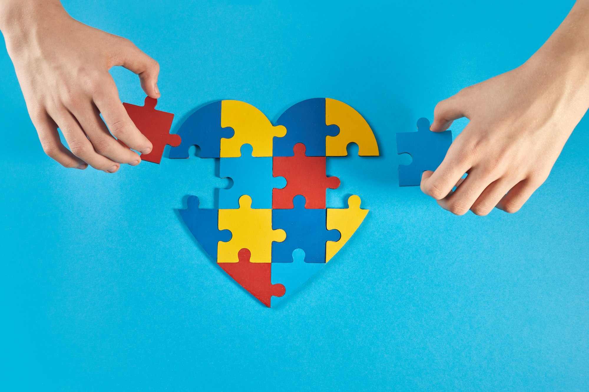 Autistic boy hands holding jigsaw puzzle heart shape. World Autism Awareness Day