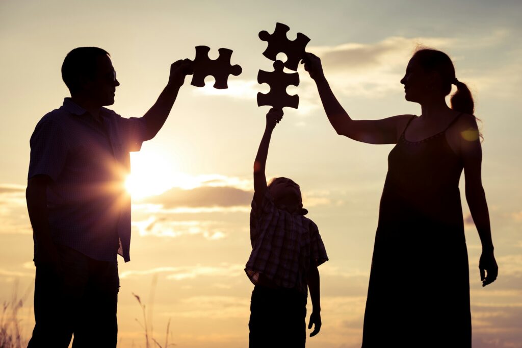 Happy family standing in the park at the sunset time.